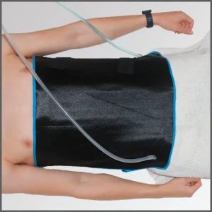 Persona en posición acostada con un intercambiador colocado sobre el abdomen, diseñado para aplicar calor, frío o contrastes térmicos durante los procesos de prevención y recuperación muscular.