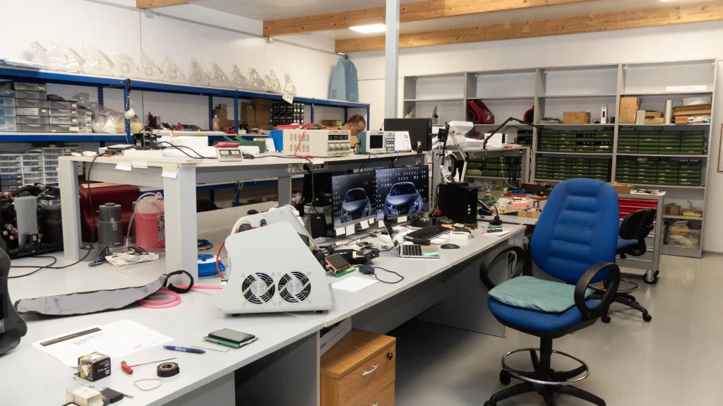 Laboratorio de una empresa fabricante de equipos de mantenimiento y recuperación muscular, con estaciones de trabajo, componentes electrónicos y equipos en proceso de desarrollo.