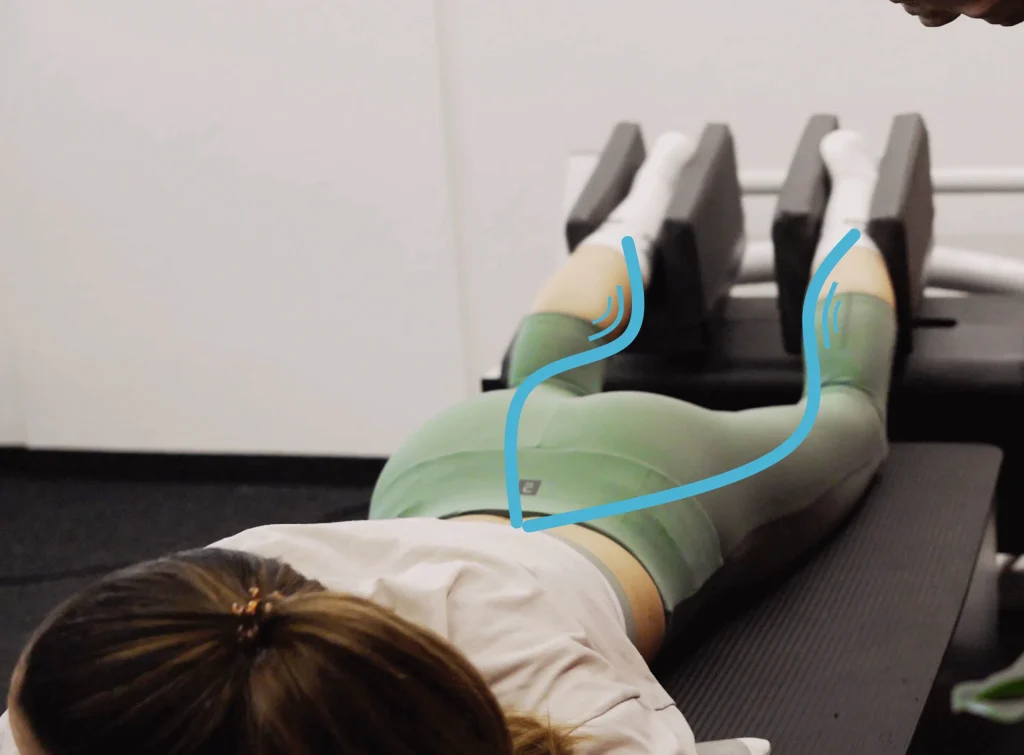 Person in training position with legs held in specialized device with Kinetic Wave technology, representing innovation in health and sports performance.